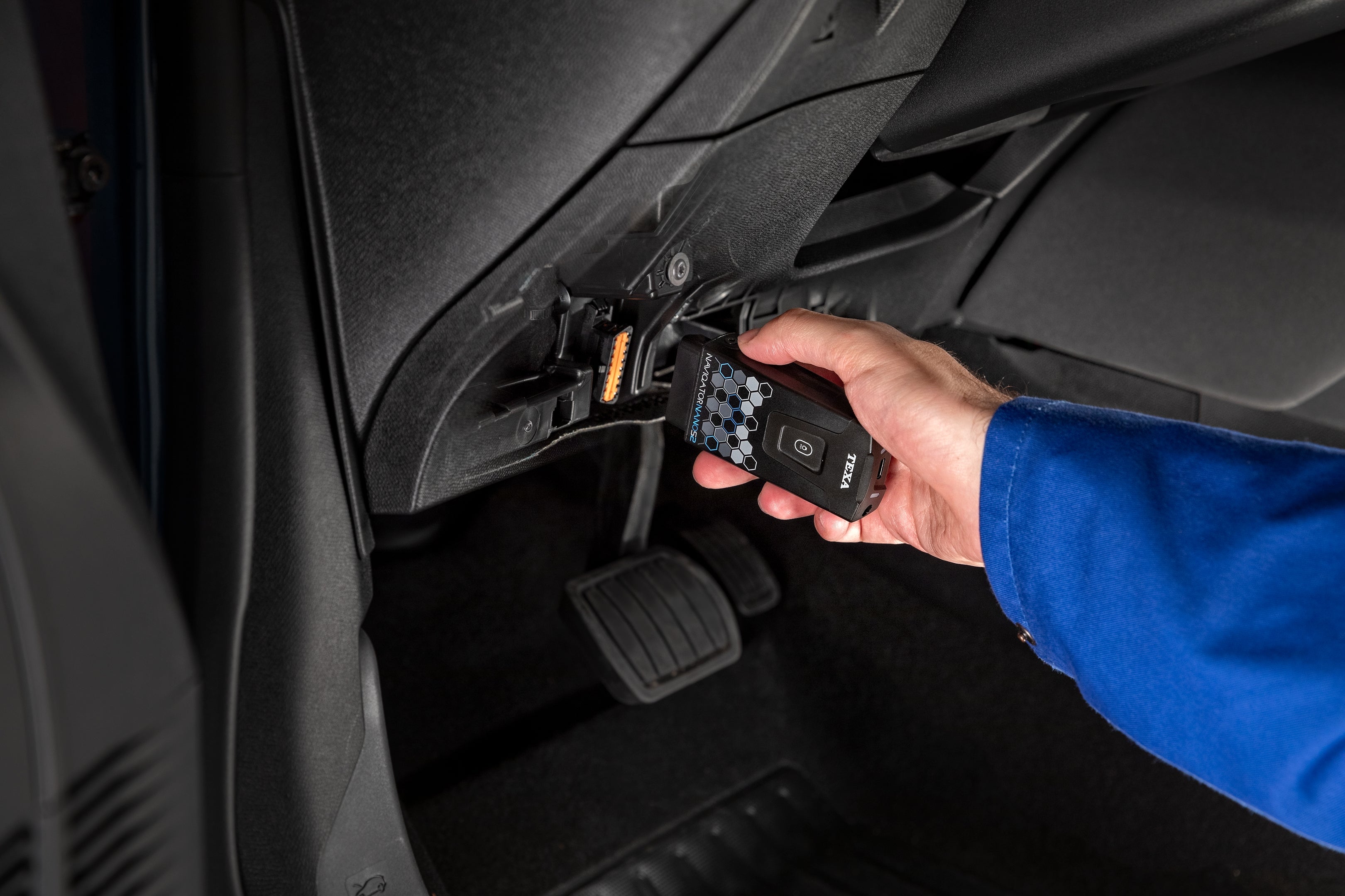 A technician plugging the TEXA NAVIGATOR NANO S 2 into a car’s diagnostic port, demonstrating its practical application in vehicle diagnostics.